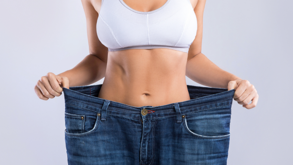 a woman pulling oversized pants away from her waist to show the results of medical weight loss programs
