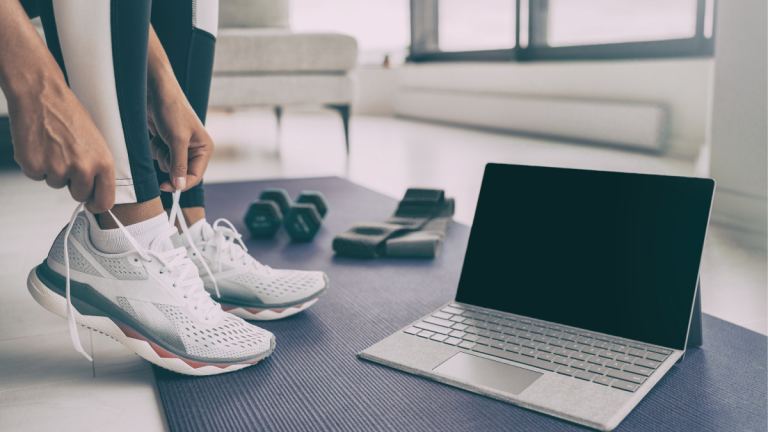 a woman puts her workout shoes on in preparation for a meeting with her online weight coach